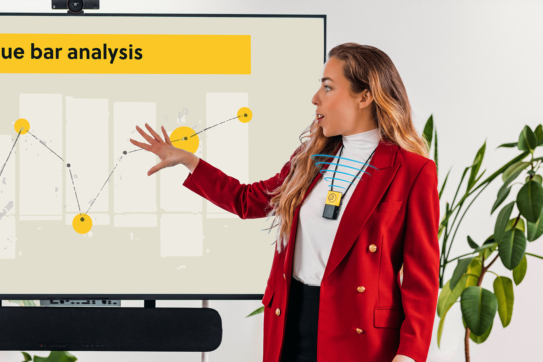 A person presenting an analysis, standing next to a screen, and amplifying their voice using a Catchbox Clip presenter microphone.