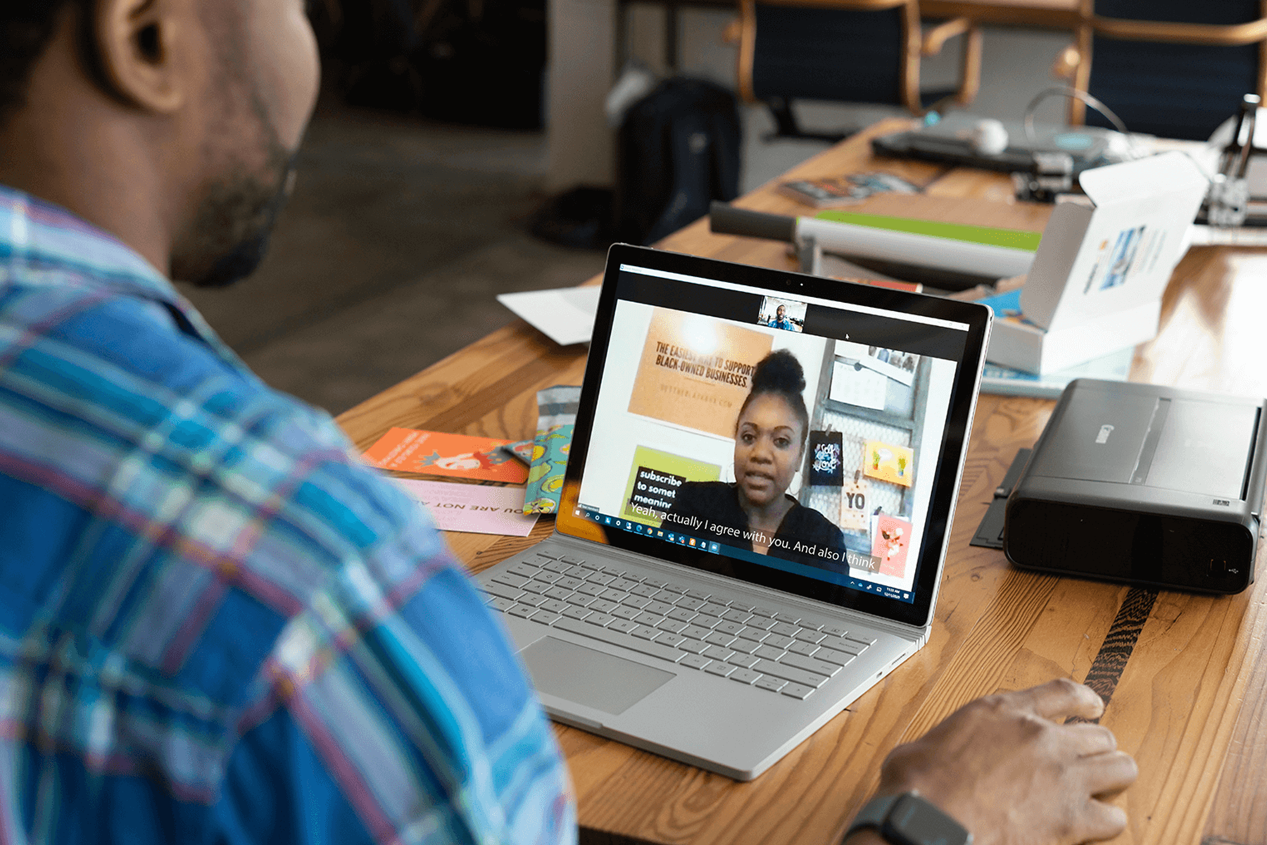 A remote worker engages with a virtual meeting, using live captions for better understanding.