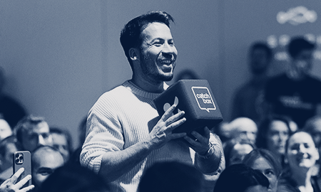 A conference attendee in the audience uses a Catchbox Cube microphone to ask a question to the presenter.