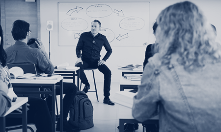 A professor wearing a Clip microphone listens attentively as a student asks a question using a Cube hrowable microphone.