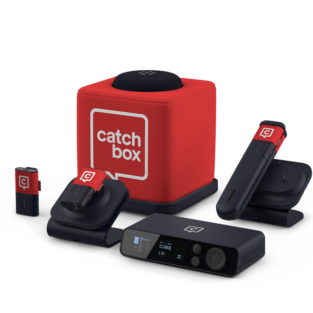 A Catchbox Plus system setup with a Hub DSP receiver, red Stick handheld microphone, red Clip wearable microphones placed on a Charging Dock, and a red Cube throwable microphone on a Charging Base.